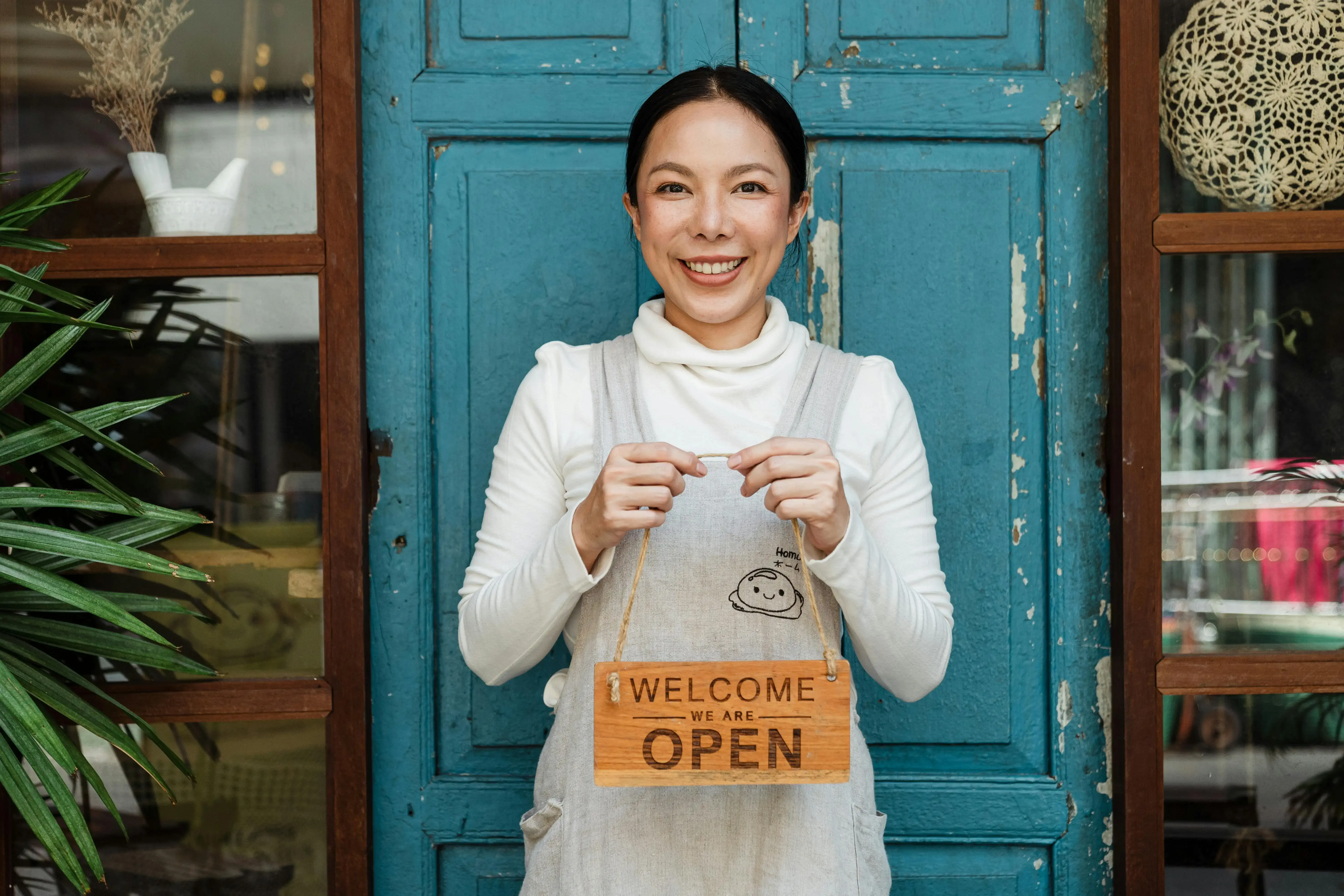 Woman holding an open sign outside a business